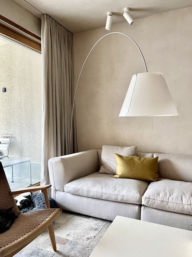 Interior with sofa, cushions, mineral plastered wall, and linen curtains in scandi rice fabric, all in harmonious natural beige tones – Embrace the soothing elegance of coordinated decor.