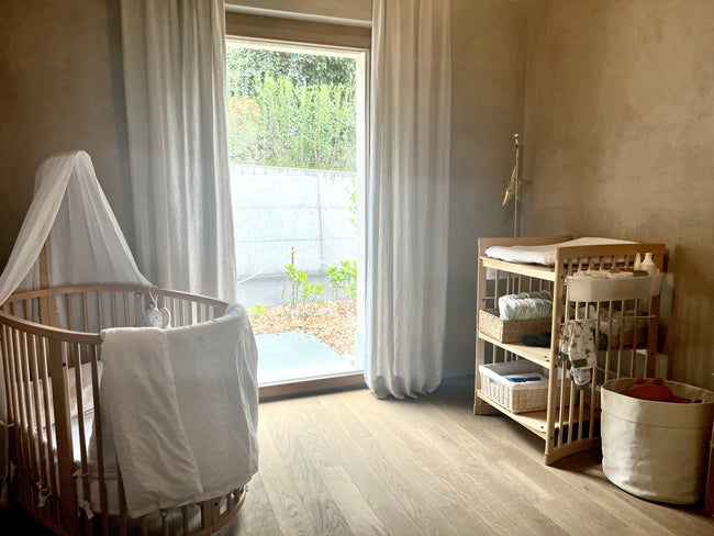 Baby nursery with wooden furniture, wooden floor, and natural materials, featuring curtains in scandi rice fabric – A cozy and natural nursery design.