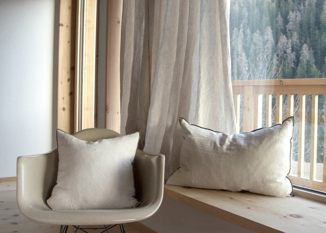 Wooden windowsill with curtain and cushions in linen fabric, natural panorama in the background - embrace the harmony of breeze oatmeal linen curtain, cushions, and a scenic natural view.