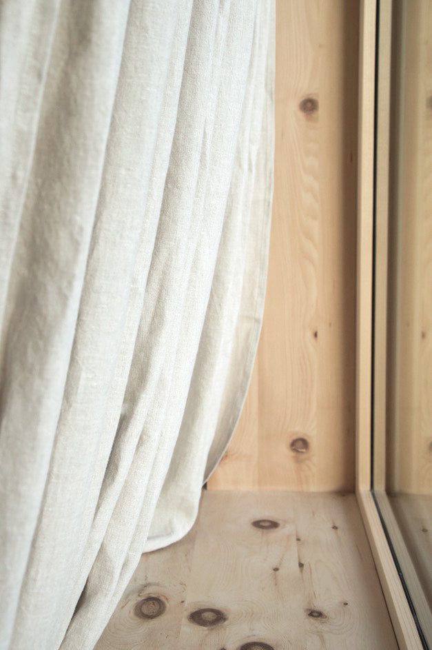 Wooden window reveal with light, flowing linen curtain - experience the elegance of breeze oatmeal linen curtain on a wooden window frame.