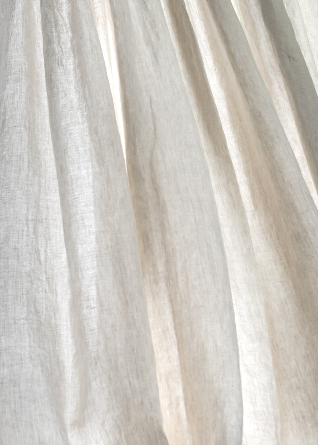 Dynamic breeze oatmeal linen curtain in motion - Unveil the exquisite natural linen texture as it gracefully flutters in the wind. Explore the elegance of ann rees' beige fabric.